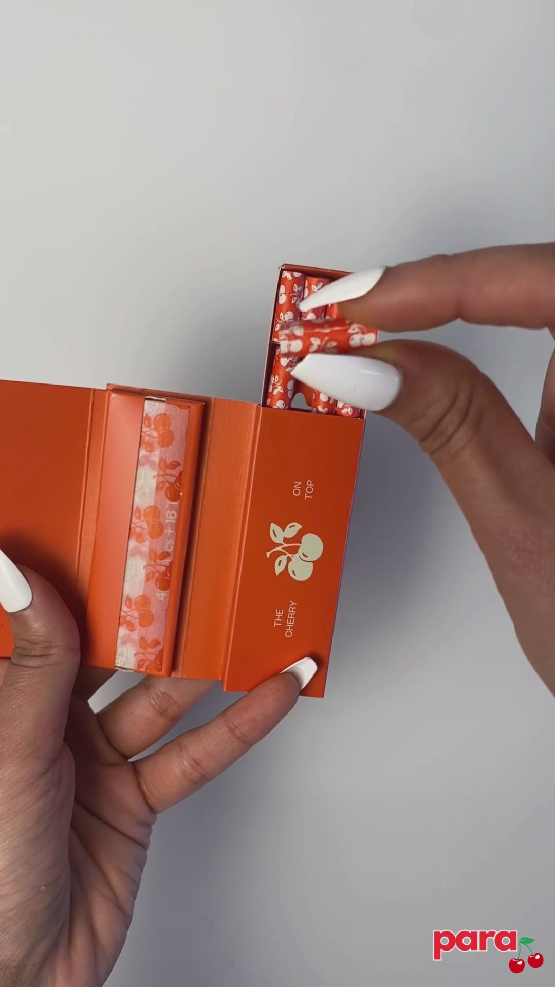 Female holding cherry-printed rolling papers for weed joints.